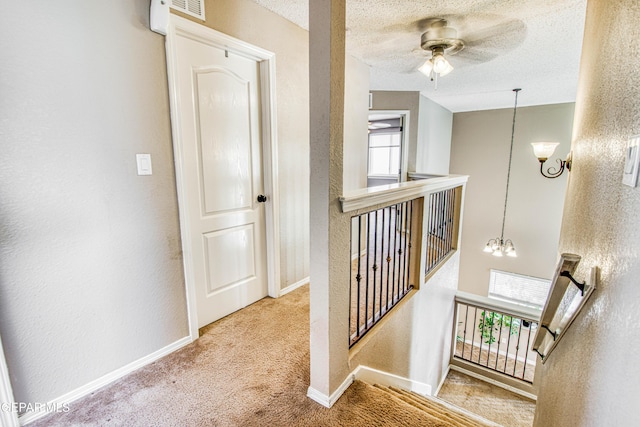 11352 Bullseye St, El Paso, TX 79934 - hallway with an upstairs landing, a chandelier, carpet floors, a textured wall, and plenty of natural light