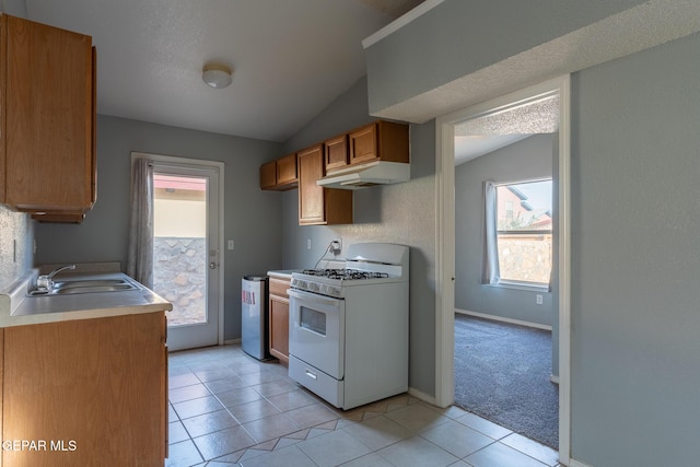6224 Rhine Bridge Dr, El Paso, TX 79934 - kitchen featuring white range with gas stovetop, under cabinet range hood, vaulted ceiling, brown cabinets, and light countertops