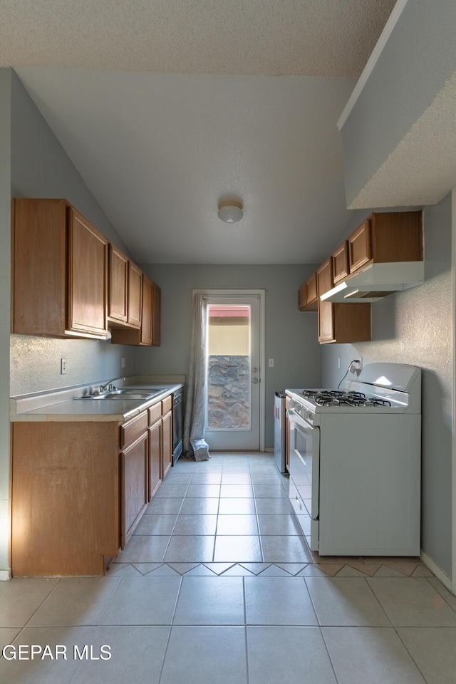 6224 Rhine Bridge Dr, El Paso, TX 79934 - kitchen featuring white range with gas stovetop, under cabinet range hood, brown cabinetry, light countertops, and light tile patterned flooring