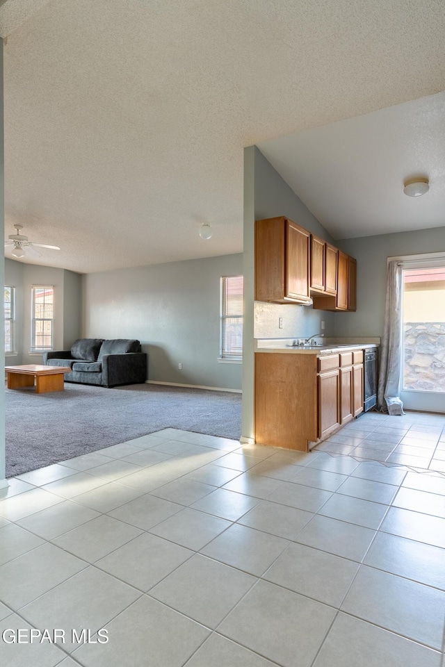 6224 Rhine Bridge Dr, El Paso, TX 79934 - kitchen with light colored carpet, a textured ceiling, open floor plan, brown cabinetry, and light countertops