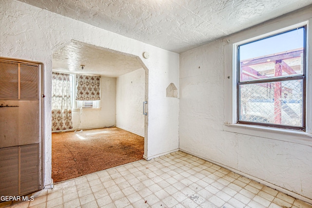 124 N Toledo Pl, El Paso, TX 79905 - spare room with a heating unit, light flooring, a textured wall, a textured ceiling, and arched walkways