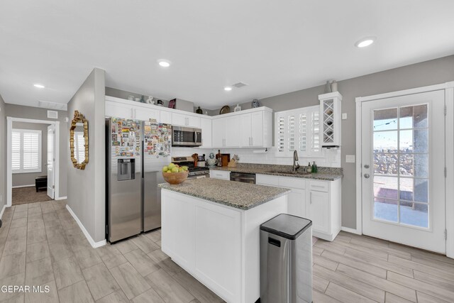13936 Garforth Ave, El Paso, TX 79928 - kitchen featuring stainless steel appliances, a sink, white cabinets, baseboards, and light stone counters
