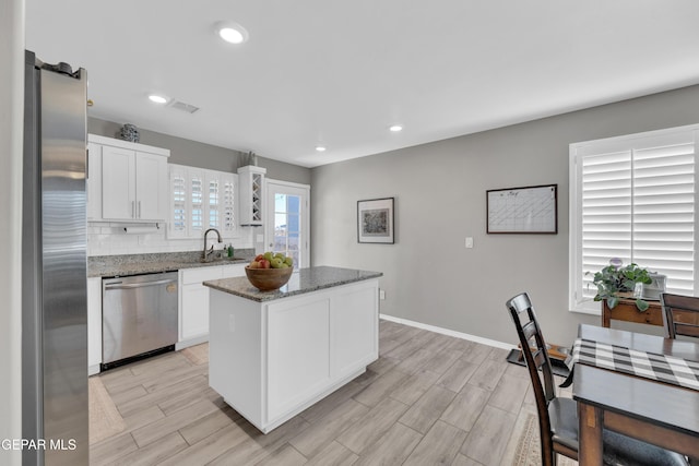 13936 Garforth Ave, El Paso, TX 79928 - kitchen with stainless steel appliances, white cabinets, a center island, stone counters, and light wood-style flooring