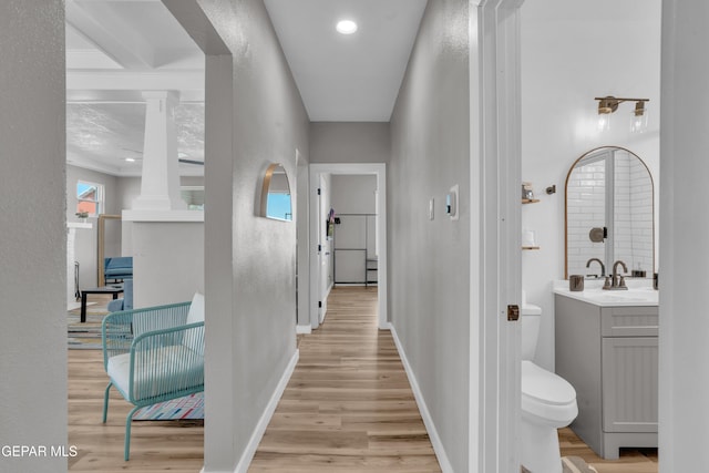 2729 Pershing Dr, El Paso, TX 79903 - corridor with light wood-style floors, a sink, baseboards, a textured wall, and ornate columns