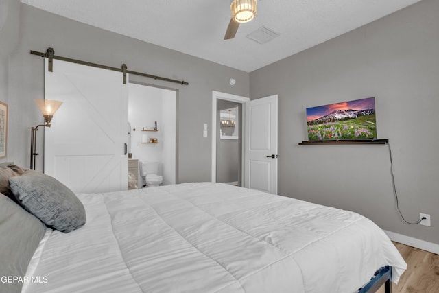 2729 Pershing Dr, El Paso, TX 79903 - bedroom with wood finished floors, a barn door, ceiling fan, and ensuite bathroom
