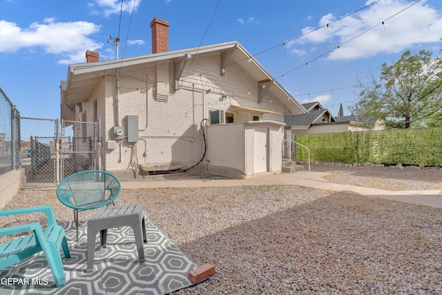2729 Pershing Dr, El Paso, TX 79903 - rear view of property featuring a chimney, brick siding, and a gate