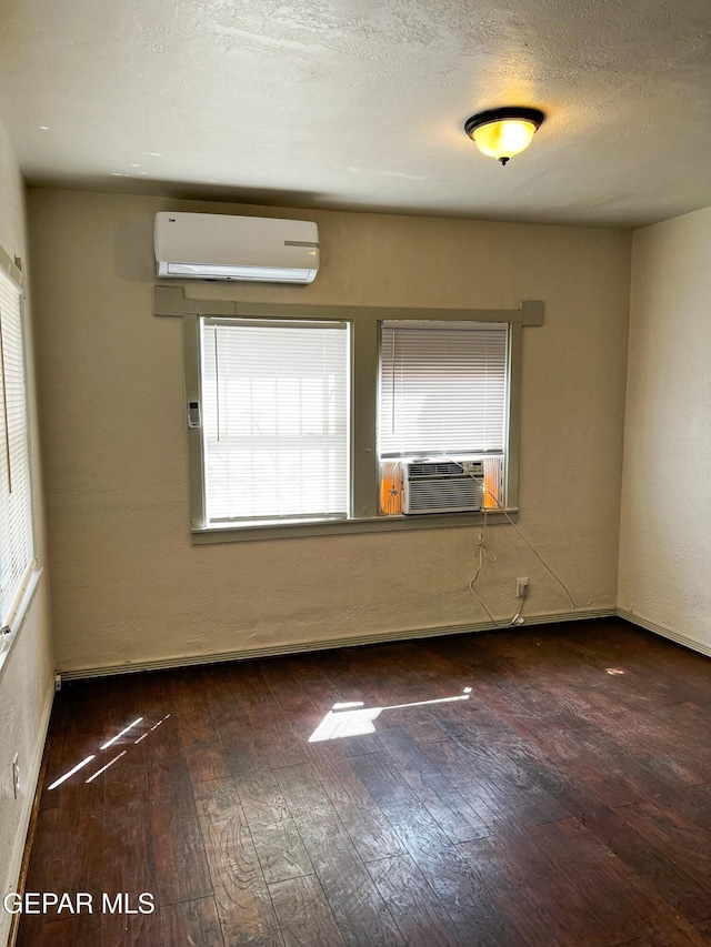 2526 Yandell Dr, El Paso, TX 79903 - spare room featuring a wall mounted AC, wood-type flooring, cooling unit, baseboards, and a textured ceiling