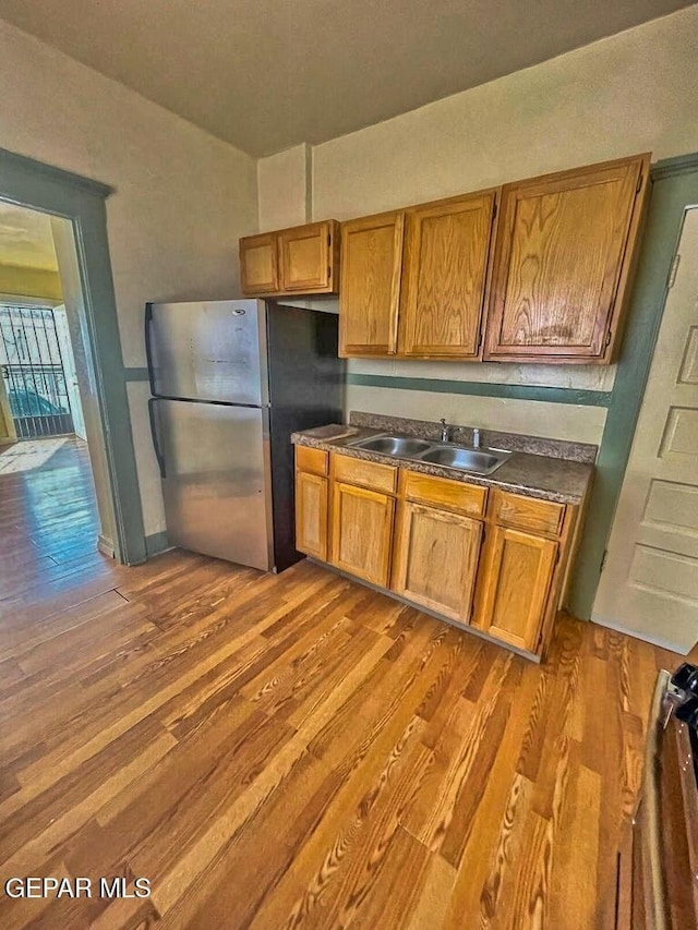 2526 Yandell Dr, El Paso, TX 79903 - kitchen featuring freestanding refrigerator, a sink, wood finished floors, dark countertops, and brown cabinetry