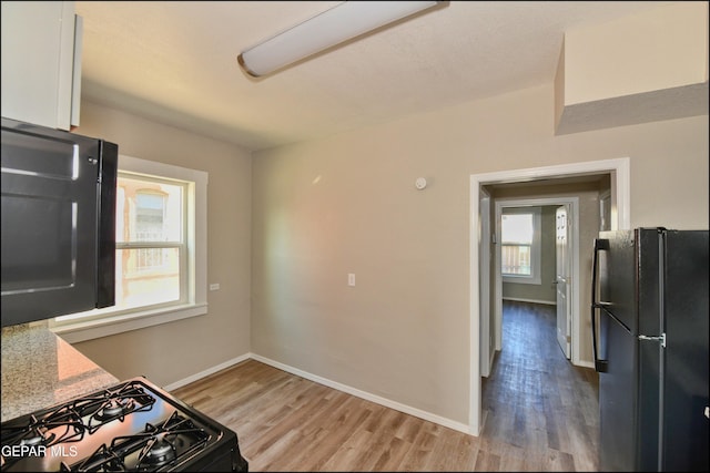 615 Arizona Ave, El Paso, TX 79902 - kitchen with black appliances, wood finished floors, baseboards, and white cabinets