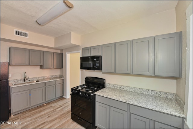 615 Arizona Ave, El Paso, TX 79902 - kitchen with black appliances, a sink, gray cabinetry, light wood finished floors, and a textured ceiling