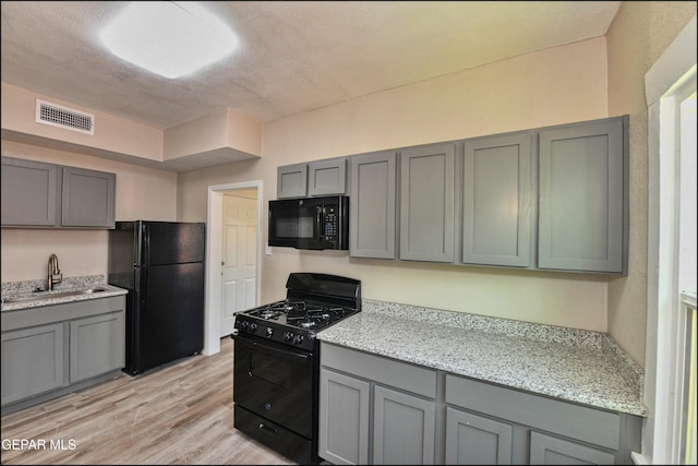 615 Arizona Ave, El Paso, TX 79902 - kitchen featuring black appliances, a sink, gray cabinetry, light wood-style floors, and light stone countertops