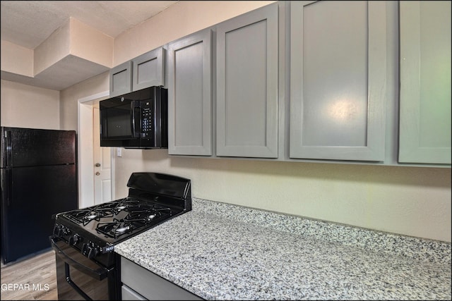 615 Arizona Ave, El Paso, TX 79902 - kitchen with black appliances, gray cabinets, light stone countertops, and light wood-type flooring