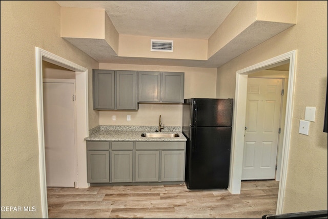 615 Arizona Ave, El Paso, TX 79902 - kitchen with freestanding refrigerator, gray cabinets, a sink, light countertops, and a textured wall