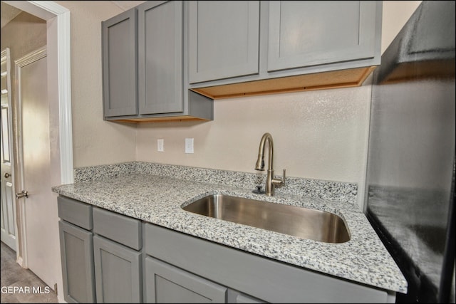 615 Arizona Ave, El Paso, TX 79902 - kitchen featuring gray cabinets, a sink, light stone countertops, and black fridge