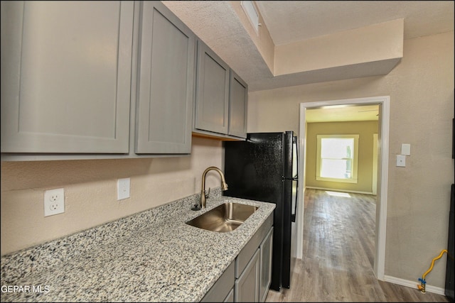 615 Arizona Ave, El Paso, TX 79902 - kitchen with a sink, gray cabinetry, light wood-type flooring, freestanding refrigerator, and light stone countertops