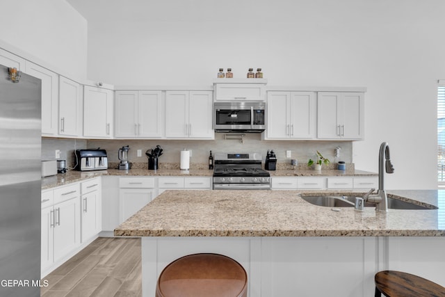 12614 Amesbury, El Paso, TX 79928 - kitchen with stainless steel appliances, a sink, a kitchen bar, tasteful backsplash, and white cabinets