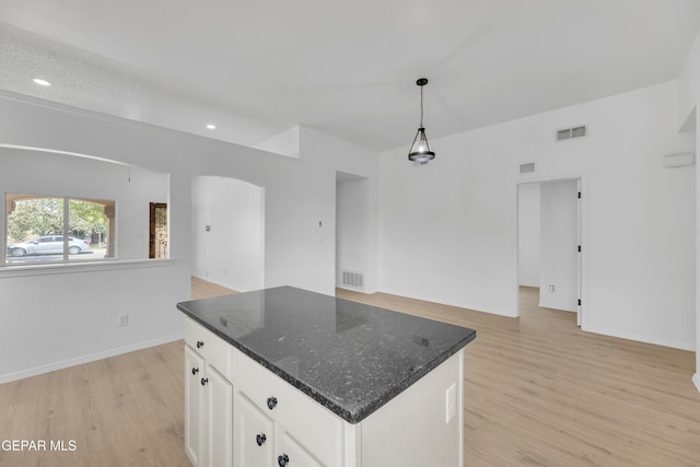 11590 Flor Liatris Dr, Socorro, TX 79927 - kitchen with light wood-style flooring, open floor plan, white cabinetry, arched walkways, and a kitchen island