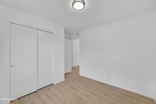 11590 Flor Liatris Dr, Socorro, TX 79927 - unfurnished bedroom with light wood-style flooring, a closet, baseboards, and a textured ceiling