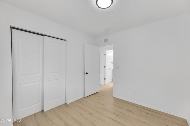 11590 Flor Liatris Dr, Socorro, TX 79927 - unfurnished bedroom with light wood-style flooring, baseboards, a closet, and a textured ceiling