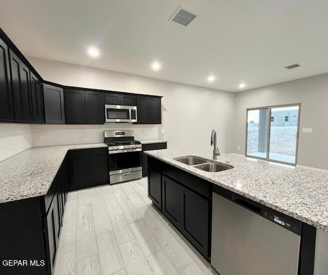 3800 Surmise St, El Paso, TX 79938 - kitchen with stainless steel appliances, a sink, dark cabinets, tasteful backsplash, and light stone countertops