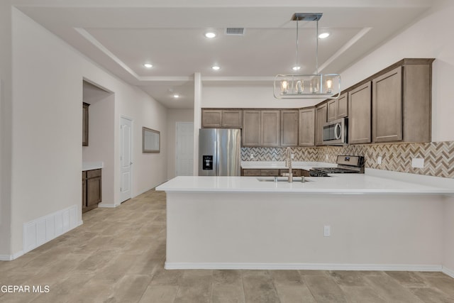 1741 Breeder Cup Way, El Paso, TX 79928 - kitchen featuring stainless steel appliances, a sink, a tray ceiling, a peninsula, and decorative backsplash