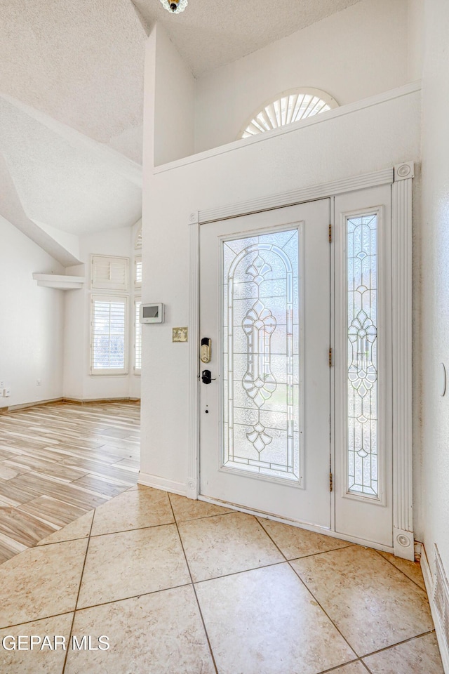 11513 Cree Ct, El Paso, TX 79936 - entryway featuring tile patterned flooring, lofted ceiling, a textured ceiling, and baseboards
