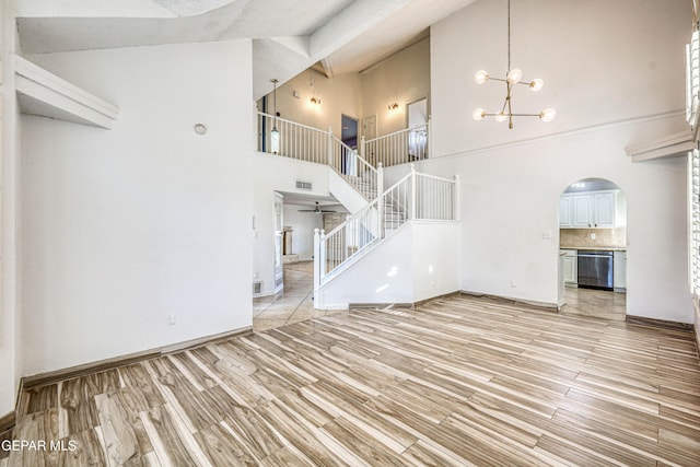 11513 Cree Ct, El Paso, TX 79936 - unfurnished living room featuring arched walkways, a high ceiling, light wood finished floors, stairs, and a chandelier