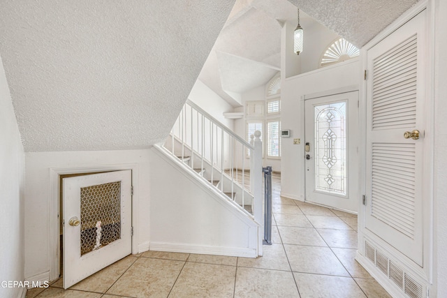 11513 Cree Ct, El Paso, TX 79936 - entryway with a textured ceiling, vaulted ceiling, light tile patterned flooring, stairs, and baseboards