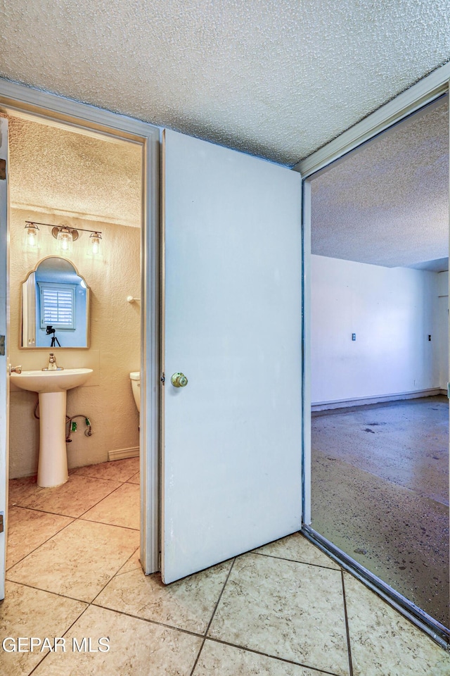 11513 Cree Ct, El Paso, TX 79936 - unfurnished bedroom featuring a textured ceiling, tile patterned floors, and ensuite bathroom