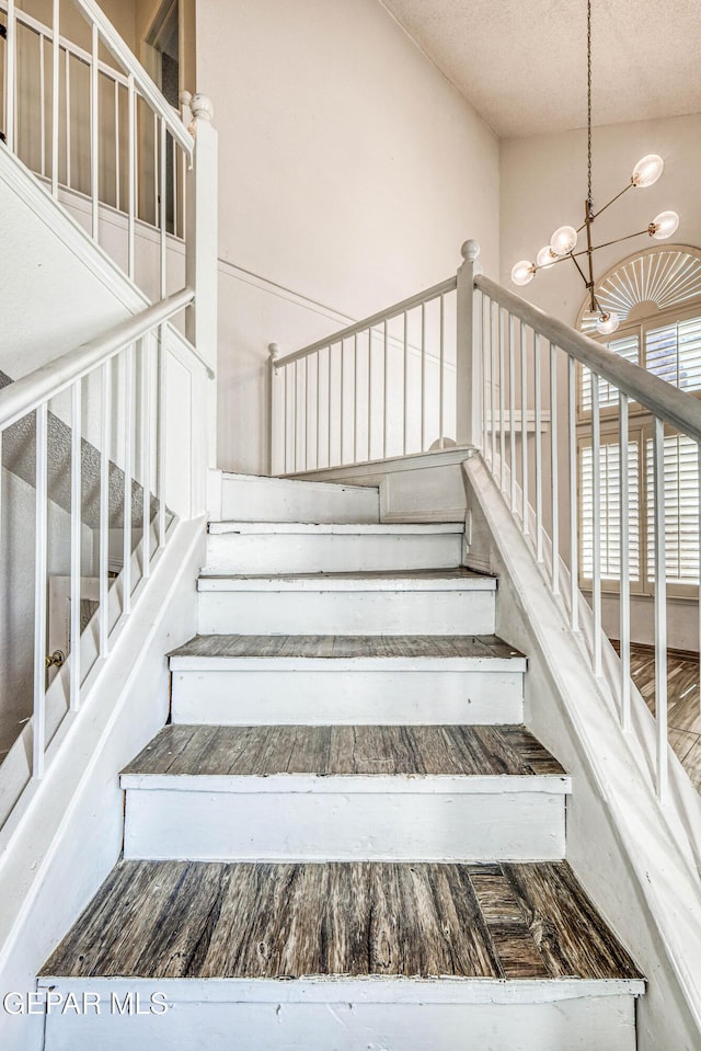 11513 Cree Ct, El Paso, TX 79936 - staircase featuring a chandelier, a textured ceiling, and lofted ceiling
