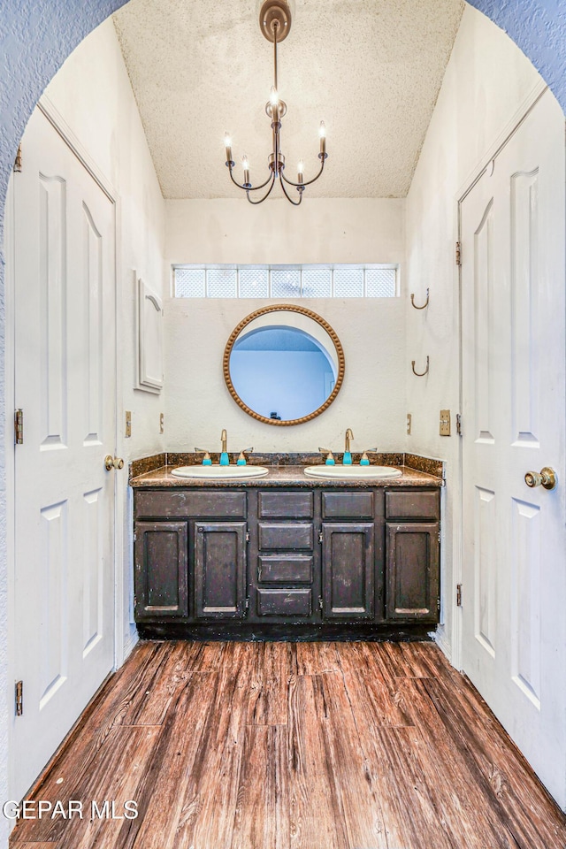 11513 Cree Ct, El Paso, TX 79936 - full bath featuring wood finished floors, double vanity, a chandelier, a textured ceiling, and plenty of natural light