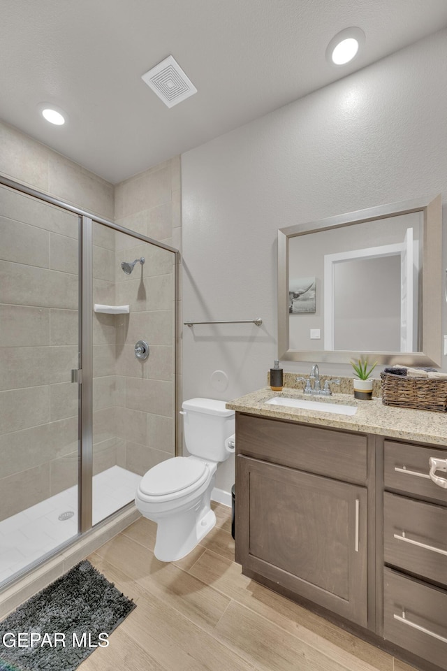 13676 Lago Vista Ave, Horizon City, TX 79928 - bathroom with toilet, vanity, a stall shower, wood finished floors, and recessed lighting