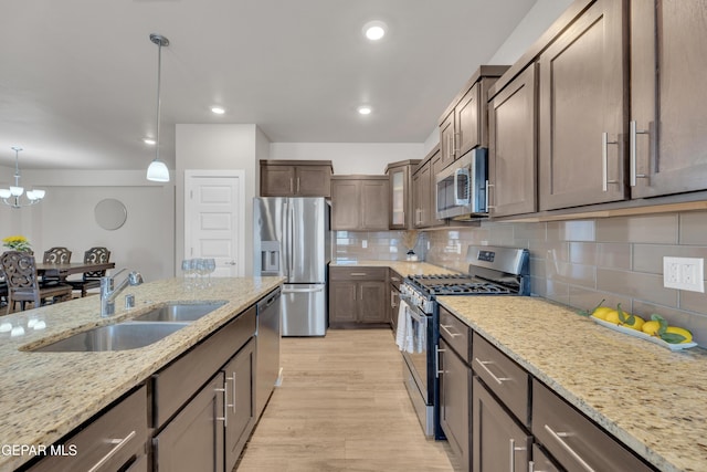 13676 Lago Vista Ave, Horizon City, TX 79928 - kitchen with appliances with stainless steel finishes, a sink, light stone countertops, light wood finished floors, and backsplash