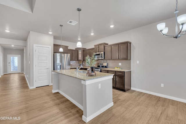 13676 Lago Vista Ave, Horizon City, TX 79928 - kitchen featuring appliances with stainless steel finishes, light wood-style flooring, dark brown cabinets, baseboards, and tasteful backsplash