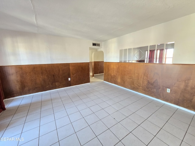 371 Medina St, El Paso, TX 79905 - unfurnished room featuring a wainscoted wall, wood walls, arched walkways, and light tile patterned floors