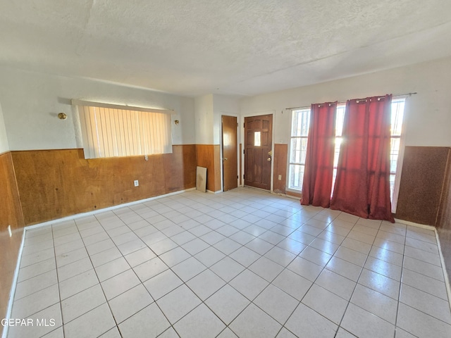 371 Medina St, El Paso, TX 79905 - tiled spare room with wainscoting, a textured ceiling, and wood walls