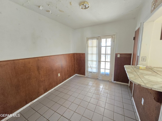 371 Medina St, El Paso, TX 79905 - unfurnished dining area with a wainscoted wall, light tile patterned flooring, and wood walls