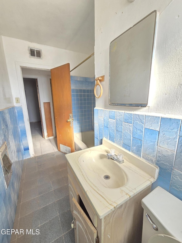 371 Medina St, El Paso, TX 79905 - bathroom with vanity, toilet, tile walls, heating unit, and tile patterned floors