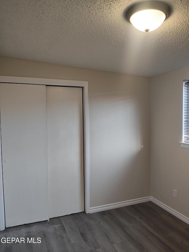 338 Maricela Dr, El Paso, TX 79915 - unfurnished bedroom featuring dark wood-style floors, a closet, a textured ceiling, and baseboards