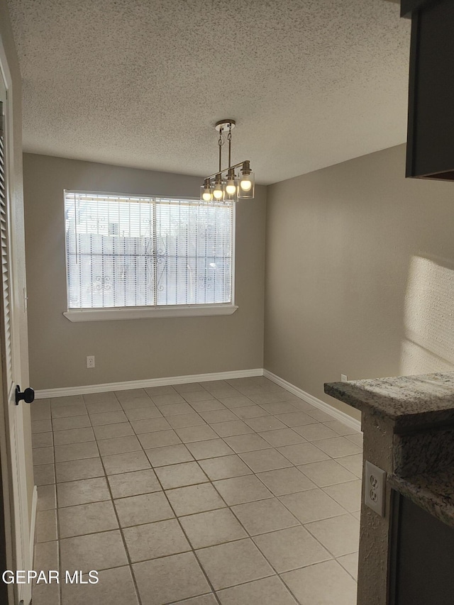 338 Maricela Dr, El Paso, TX 79915 - unfurnished dining area featuring light tile patterned flooring, a textured ceiling, and baseboards