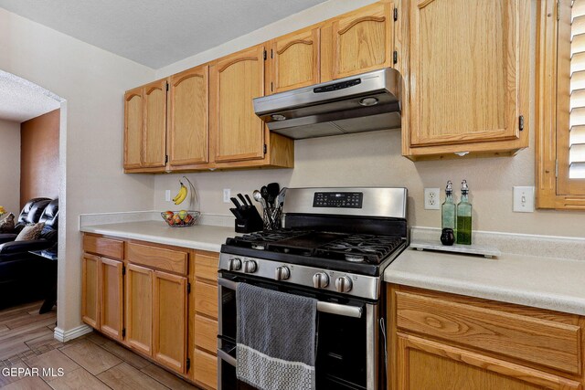14025 Stoutland Ln, El Paso, TX 79928 - kitchen with stainless steel gas range, under cabinet range hood, light countertops, and wood tiled floors