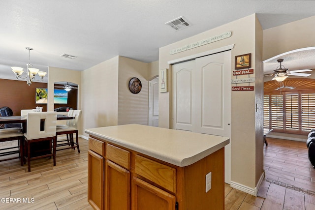 14025 Stoutland Ln, El Paso, TX 79928 - kitchen with a ceiling fan, light wood finished floors, a kitchen island, and a chandelier
