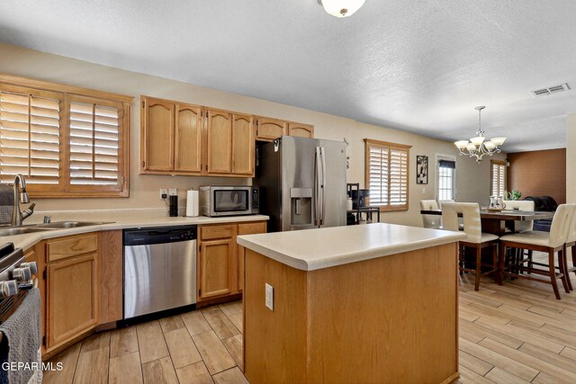 14025 Stoutland Ln, El Paso, TX 79928 - kitchen with appliances with stainless steel finishes, a chandelier, a sink, light wood-style flooring, and a kitchen island