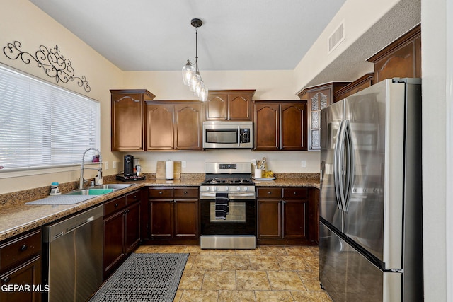 14309 Coyote Trl, El Paso, TX 79938 - kitchen with appliances with stainless steel finishes, decorative light fixtures, dark brown cabinets, and a sink