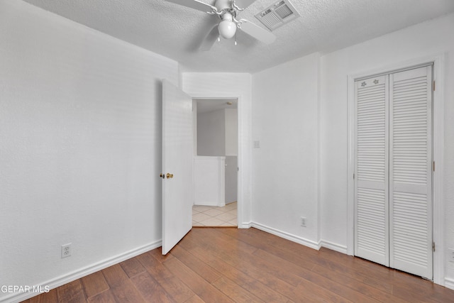 5424 Fire Ridge Cir, El Paso, TX 79932 - unfurnished bedroom featuring wood-type flooring, baseboards, a textured ceiling, a closet, and a ceiling fan