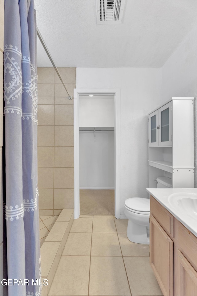 5424 Fire Ridge Cir, El Paso, TX 79932 - full bathroom with tile patterned floors, tiled shower, toilet, vanity, and a walk in closet