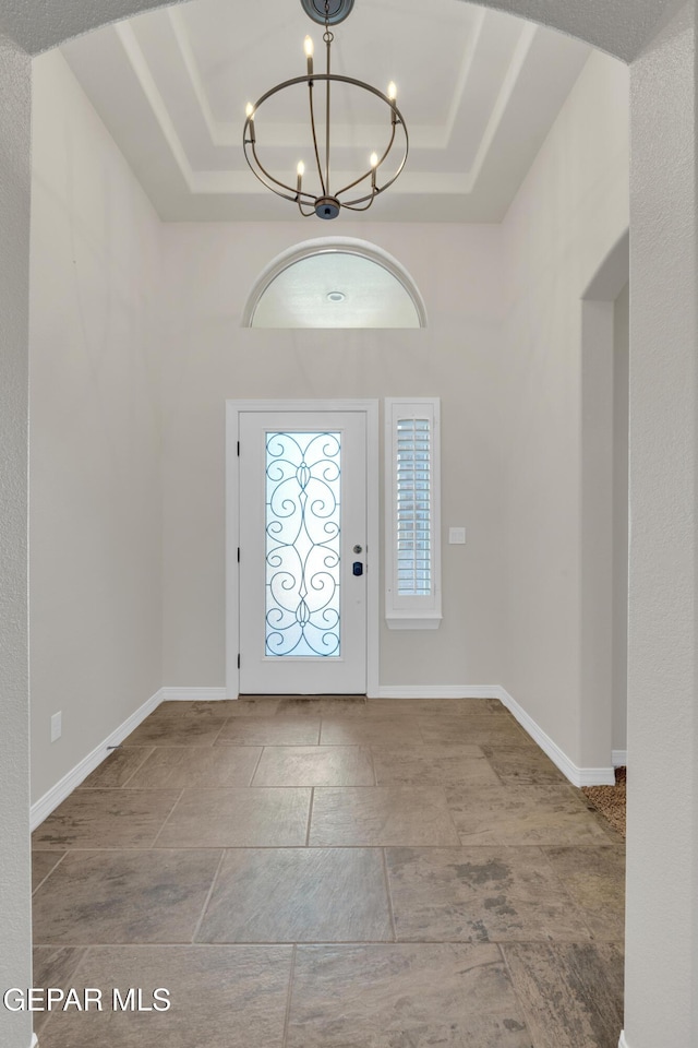 12776 Runway Ave, El Paso, TX 79928 - entryway with a raised ceiling, a chandelier, baseboards, arched walkways, and stone finish flooring