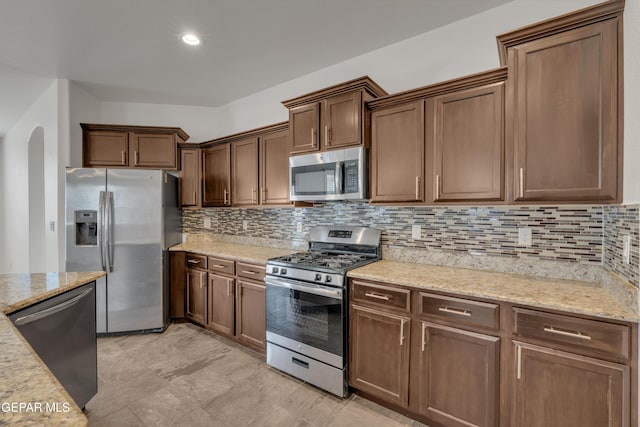 12776 Runway Ave, El Paso, TX 79928 - kitchen with appliances with stainless steel finishes, arched walkways, backsplash, and light stone counters