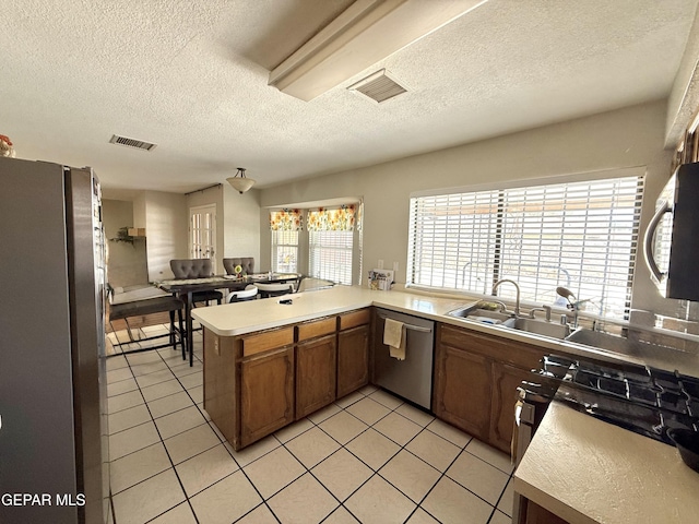 3224 Seabrook St, El Paso, TX 79936 - kitchen featuring stainless steel appliances, a textured ceiling, light tile patterned floors, light countertops, and brown cabinets