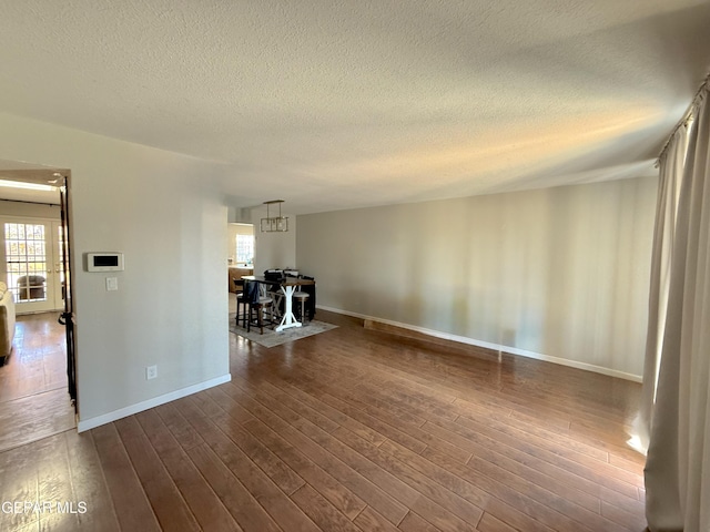 3224 Seabrook St, El Paso, TX 79936 - unfurnished living room featuring a textured ceiling, dark wood-type flooring, baseboards, and a chandelier